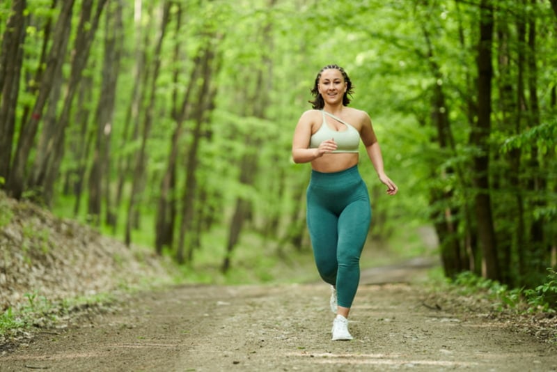 Curvy woman jogging through the woods